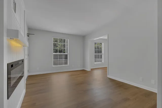 an empty room with wooden floor and windows