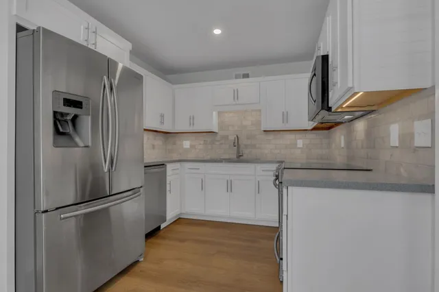 a kitchen with stainless steel appliances granite countertop grey cabinets a stove a sink and dishwasher