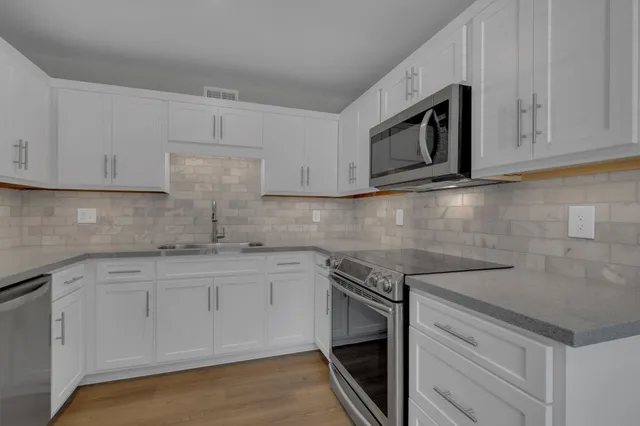 a kitchen with granite countertop white cabinets stainless steel appliances and sink