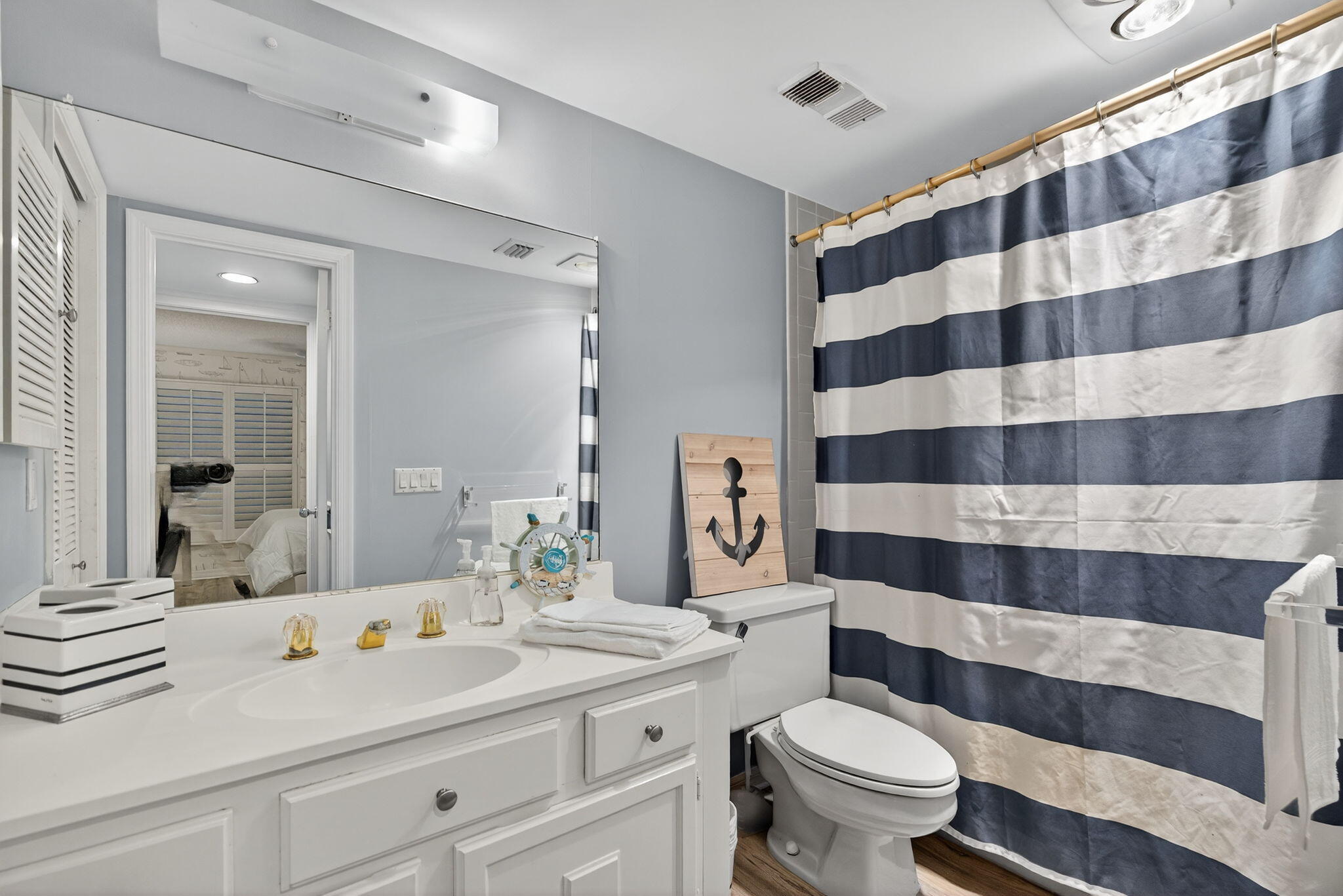 390 Northeast Edgewater Drive, Unit 403 Stuart, FL 34996 - Photo 20 of 46 a bathroom with a sink a toilet a mirror and shower curtain