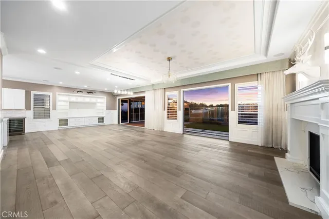an empty room with wooden floor fireplace and windows