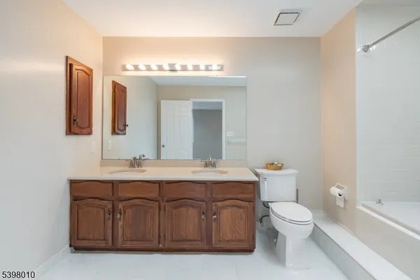 a bathroom with a double vanity sink toilet mirror and bathtub