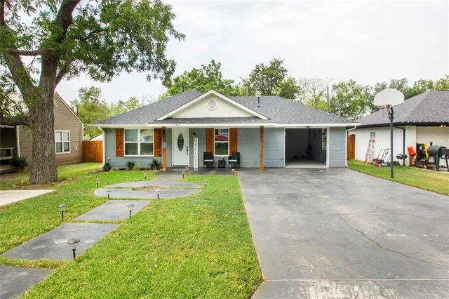 a view of a white house with a small yard plants and a large tree