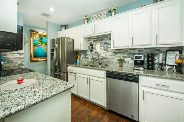 a kitchen with stainless steel appliances granite countertop a sink refrigerator and cabinets