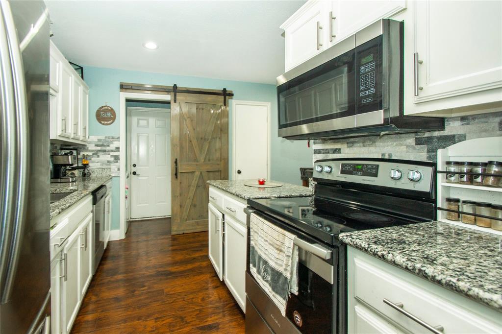 106 South 4th Street Celeste, TX 75423 - Photo 13 of 28 a kitchen with stainless steel appliances kitchen island granite countertop a stove and a wooden cabinets
