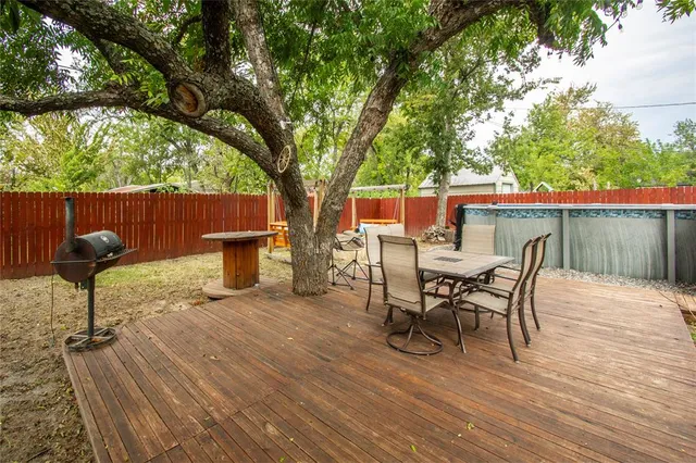 a view of a patio with table and chairs potted plants and large tree