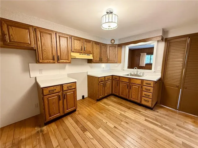 a kitchen with stainless steel appliances granite countertop a sink dishwasher stove and refrigerator with wooden floor