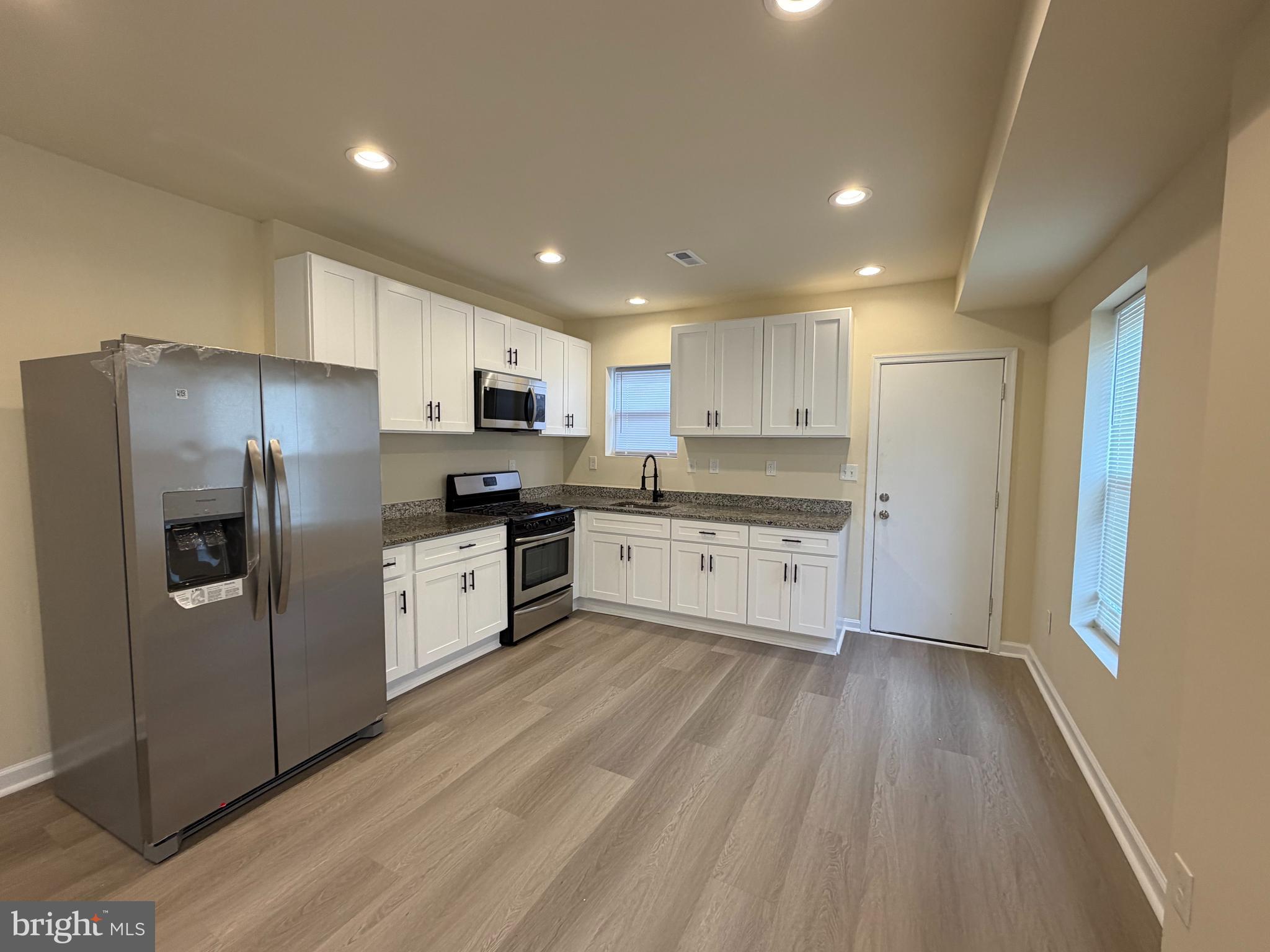 601 North Clinton Street Baltimore, MD 21205 - Photo 6 of 12 a kitchen with granite countertop a refrigerator oven a sink dishwasher and white cabinets with wooden floor