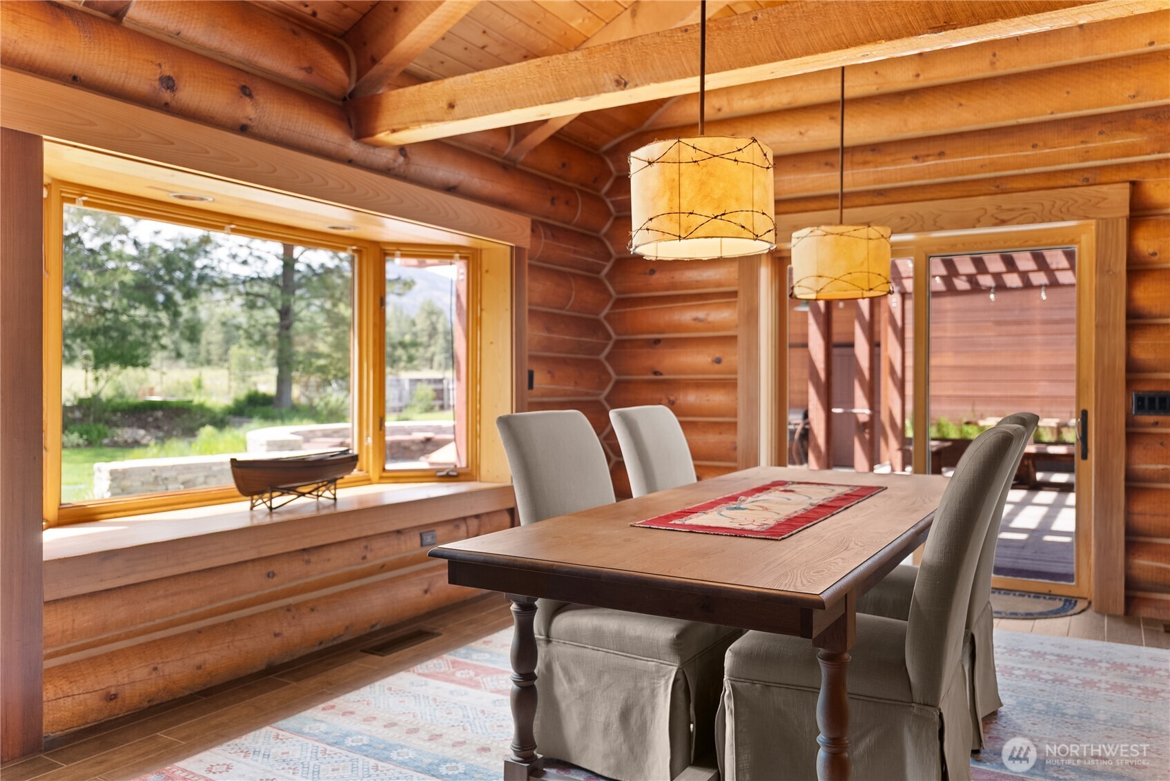 179 Wolf Creek Road Winthrop, WA 98862 - Photo 12 of 40 a view of a dining room with furniture large windows and wooden floor