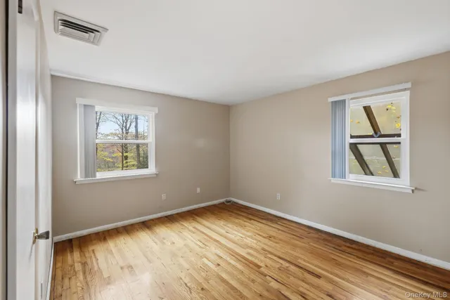 a view of empty room with window and wooden floor