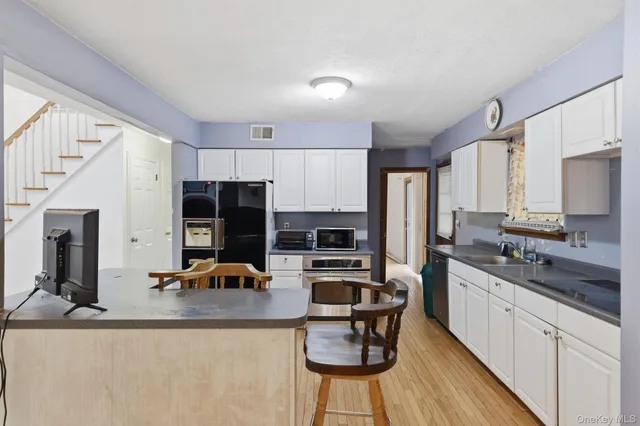 a kitchen with stainless steel appliances granite countertop a refrigerator a stove a sink dishwasher a stove and white countertops with wooden floor