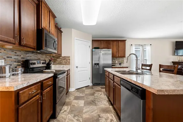 a kitchen with stainless steel appliances granite countertop a sink stove and refrigerator