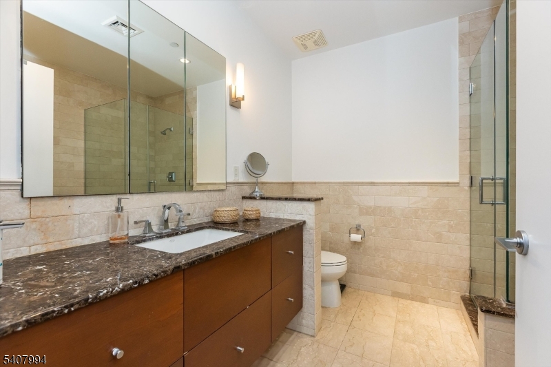 85 Park Avenue, Unit 205 Glen Ridge, NJ 07028 - Photo 23 of 37 a bathroom with a granite countertop sink a toilet and a mirror