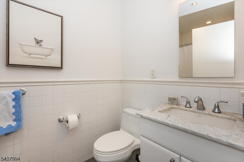 85 Park Avenue, Unit 205 Glen Ridge, NJ 07028 - Photo 33 of 37 a bathroom with a granite countertop sink a toilet and a mirror