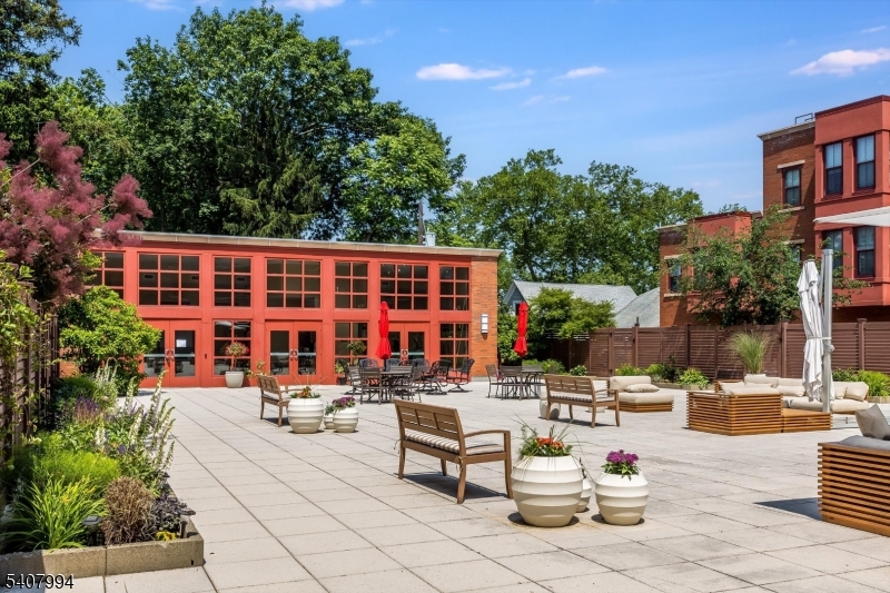 85 Park Avenue, Unit 205 Glen Ridge, NJ 07028 - Photo 36 of 37 a view of a patio with dining table and chairs with plants and palm trees