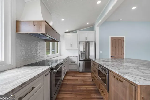 a kitchen with stainless steel appliances granite countertop a sink and a refrigerator
