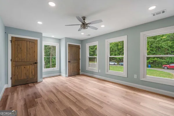 a view of an empty room with a window and wooden floor