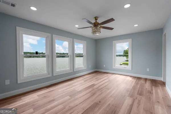 a view of an empty room with a window and wooden floor