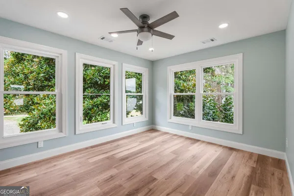 a view of an empty room with wooden floor and a window