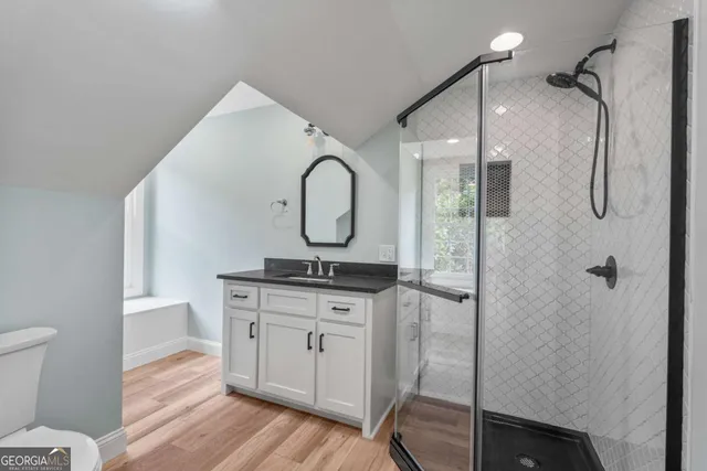 a spacious bathroom with a granite countertop sink a toilet and a shower