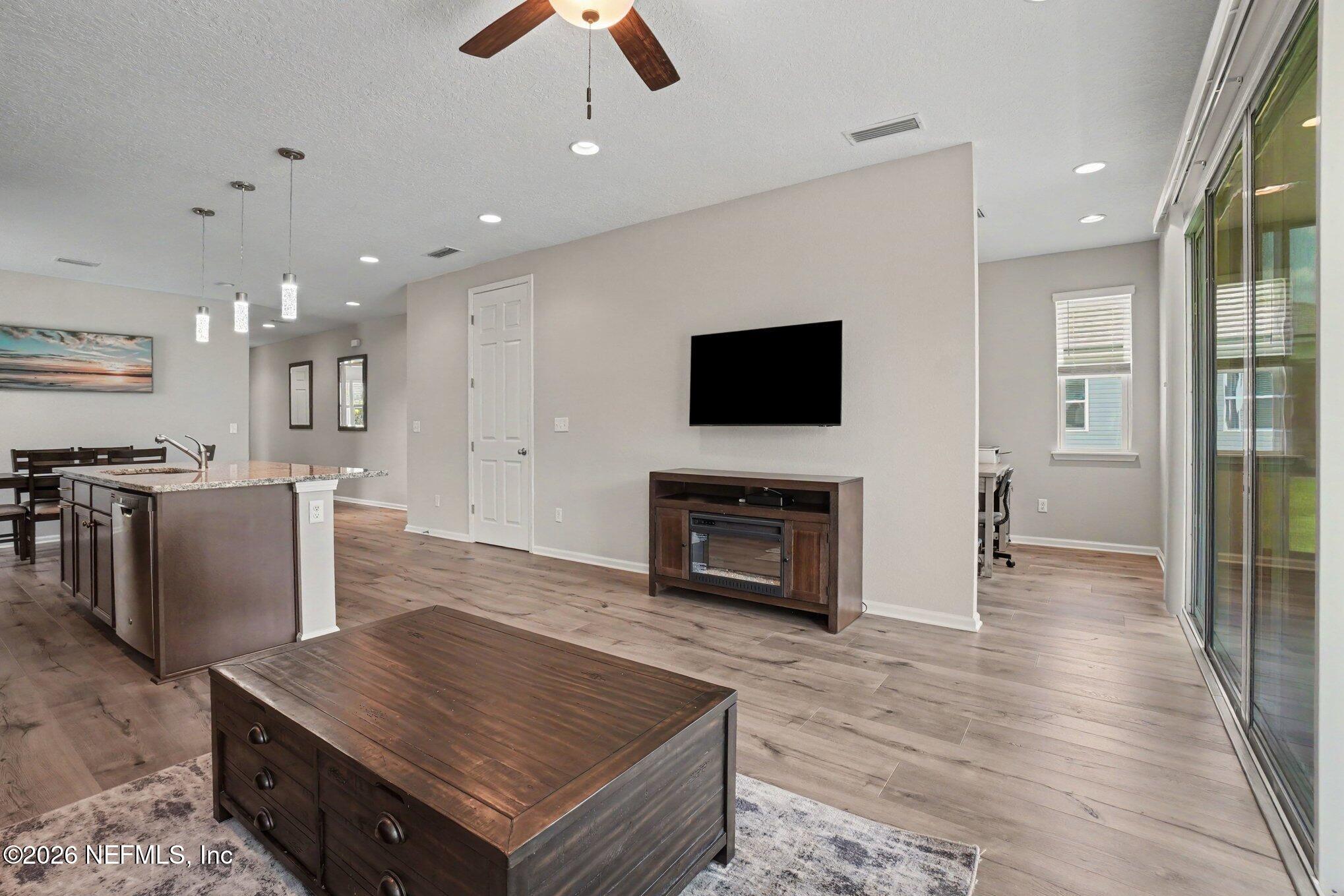 4630 Pine Ridge Parkway Middleburg, FL 32068 - Photo 5 of 35 a living room with stainless steel appliances kitchen island furniture a fireplace a flat screen tv and view kitchen