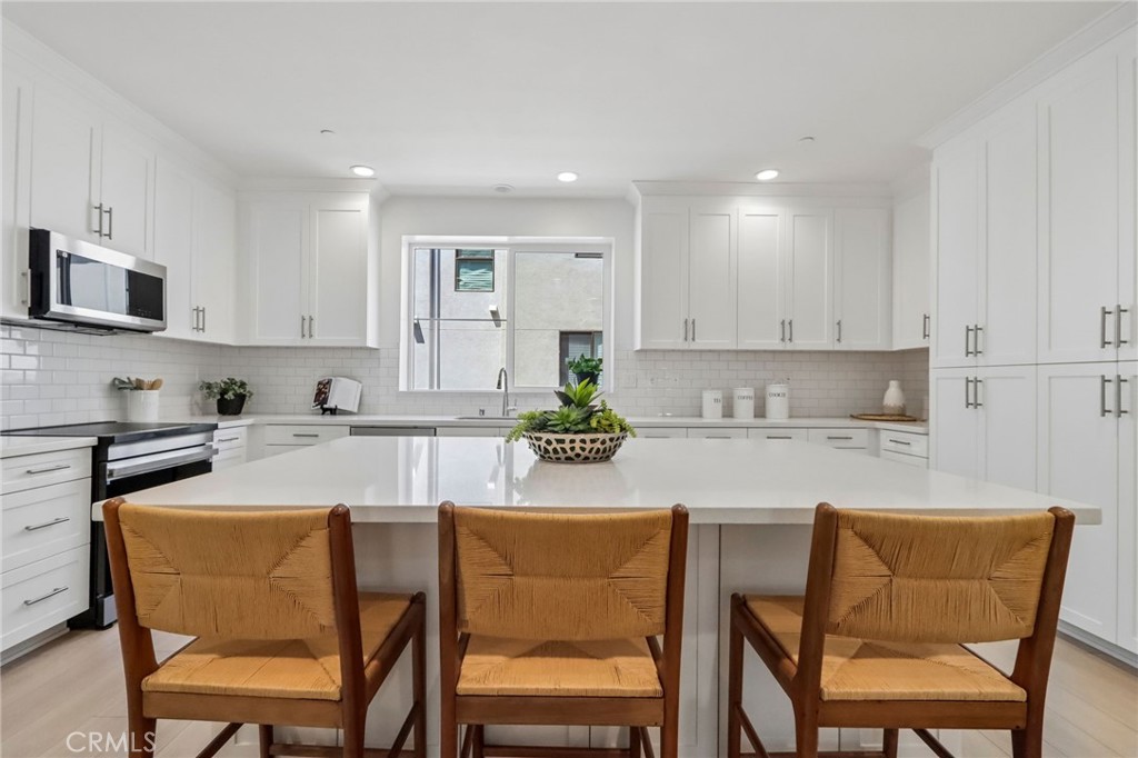5868 Linden, Unit 6 Long Beach, CA 90805 - Photo 4 of 34 a kitchen with stainless steel appliances granite countertop a stove a sink a microwave a dining table and chairs