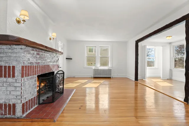 a view of an empty room with fire place and windows