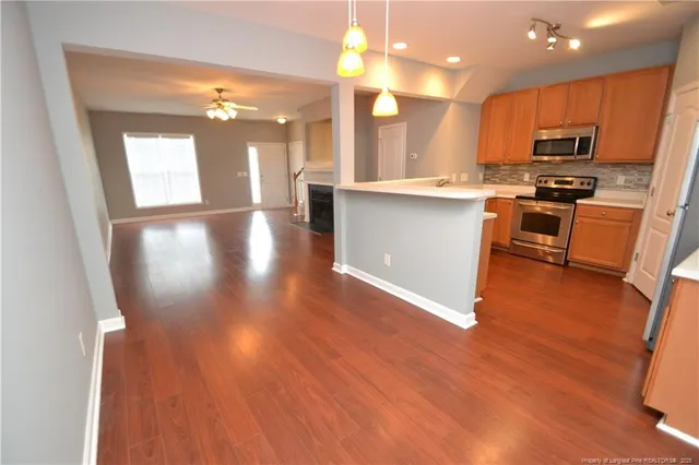 a kitchen with stainless steel appliances granite countertop a stove a refrigerator a sink a microwave oven with wooden floor