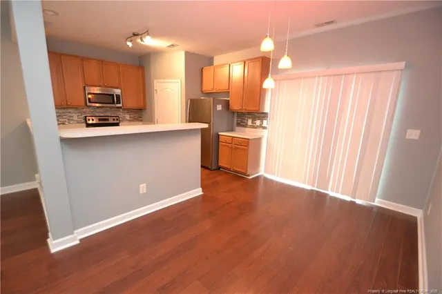 a kitchen with stainless steel appliances granite countertop a refrigerator a sink dishwasher a stove and white countertops with wooden floor