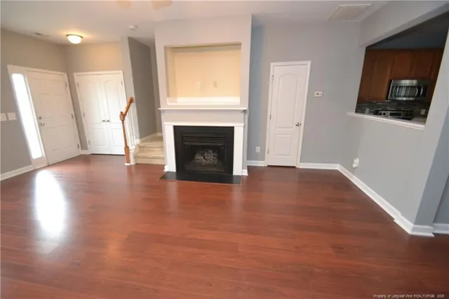 a view of a livingroom with wooden floor and a fireplace