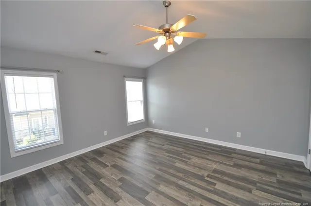a view of an empty room with a window and wooden floor