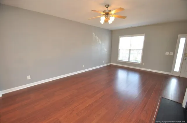 an empty room with wooden floor and window