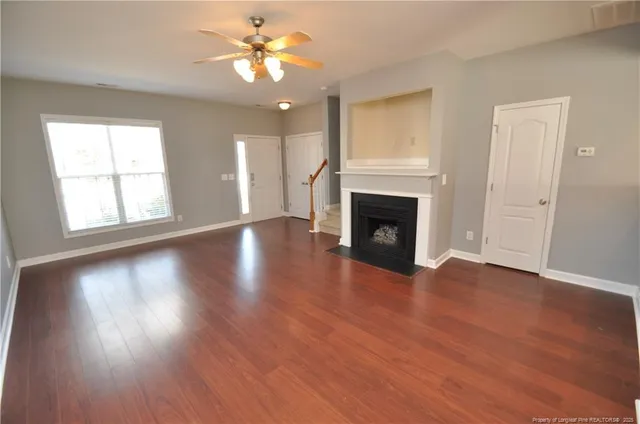 an empty room with wooden floor fireplace and windows