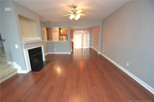 a view of a livingroom with wooden floor a fireplace and windows