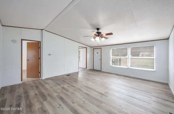 a view of an empty room with a window and wooden floor
