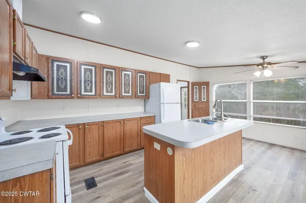 a kitchen with stainless steel appliances granite countertop a stove a refrigerator a sink dishwasher and wooden cabinets with wooden floor