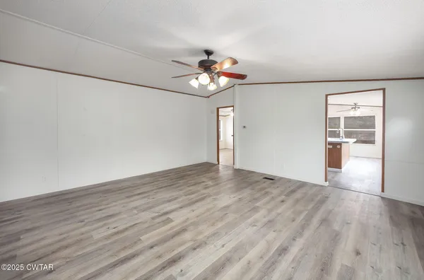 a view of an empty room with a window and wooden floor
