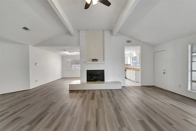 an empty room with wooden floor a fireplace and windows