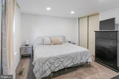 a bedroom with a bed and a flat tv screen on dresser