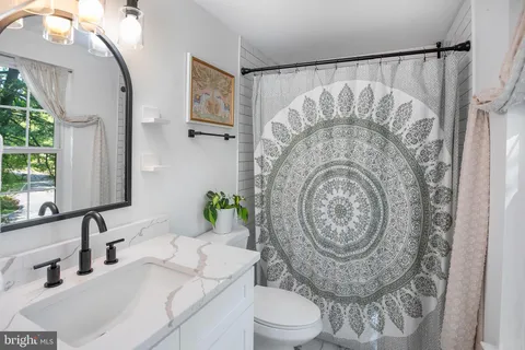 a bathroom with a granite countertop toilet a sink and a mirror