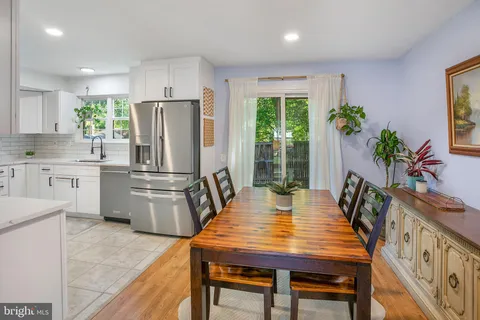 a kitchen with stainless steel appliances granite countertop a table chairs and a refrigerator