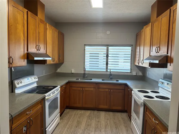 a kitchen with stainless steel appliances granite countertop a sink a stove cabinets counter space and a window