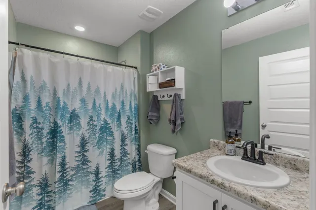 a bathroom with a granite countertop sink toilet and shower