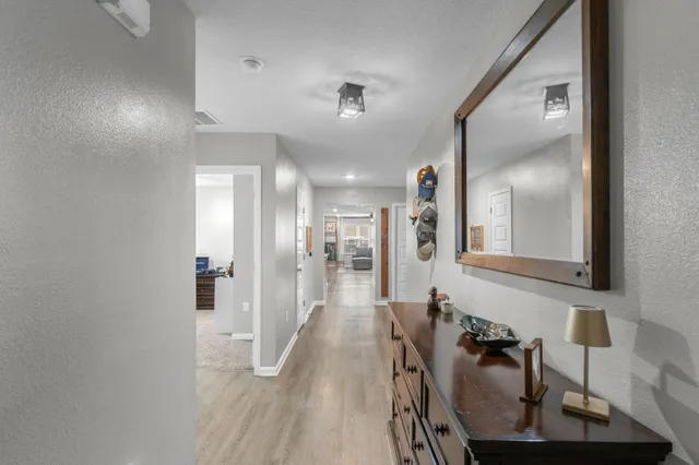 a view of a hallway with wooden floor and a bathroom