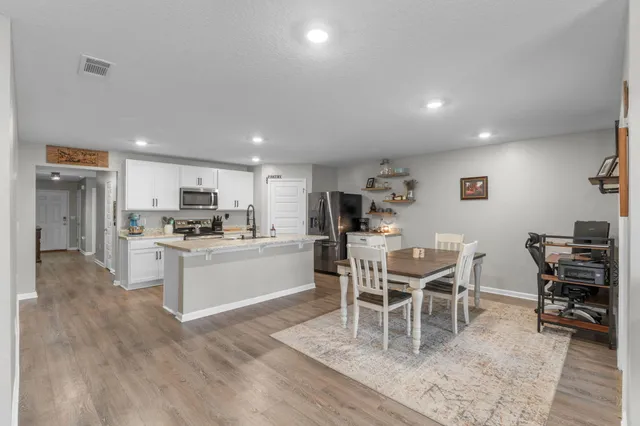 a kitchen with stainless steel appliances kitchen island granite countertop a dining table chairs and view living room