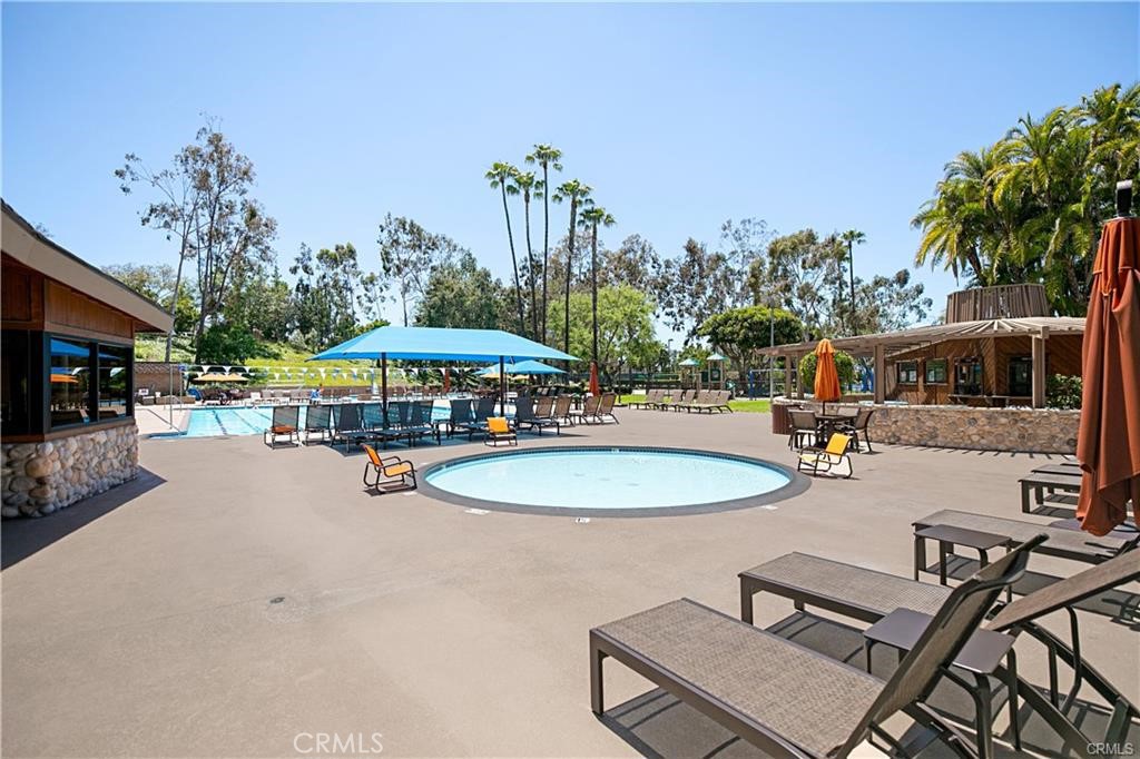 25032 Crystal Circle Lake Forest, CA 92630 - Photo 52 of 54 a view of a swimming pool with a table and chairs under an umbrella