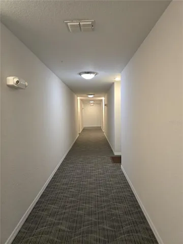 a view of a hallway with wooden floor and a large mirror