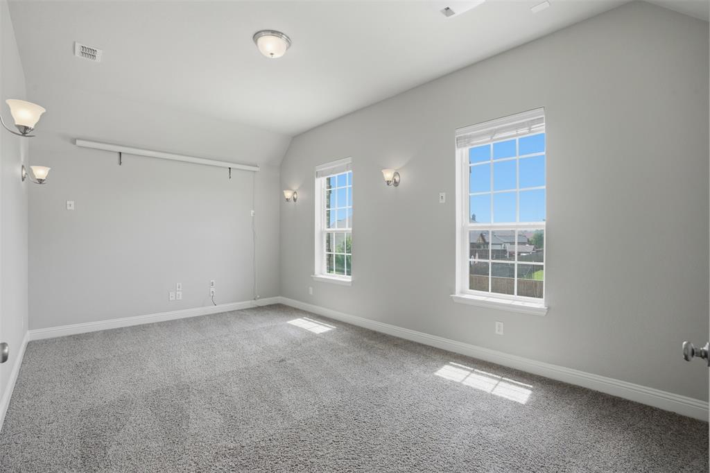 2217 Riviera Drive Little Elm, TX 75068 - Photo 19 of 36 Carpeted room featuring two double-hung windows with grids, neutral gray wall paint, and white trim