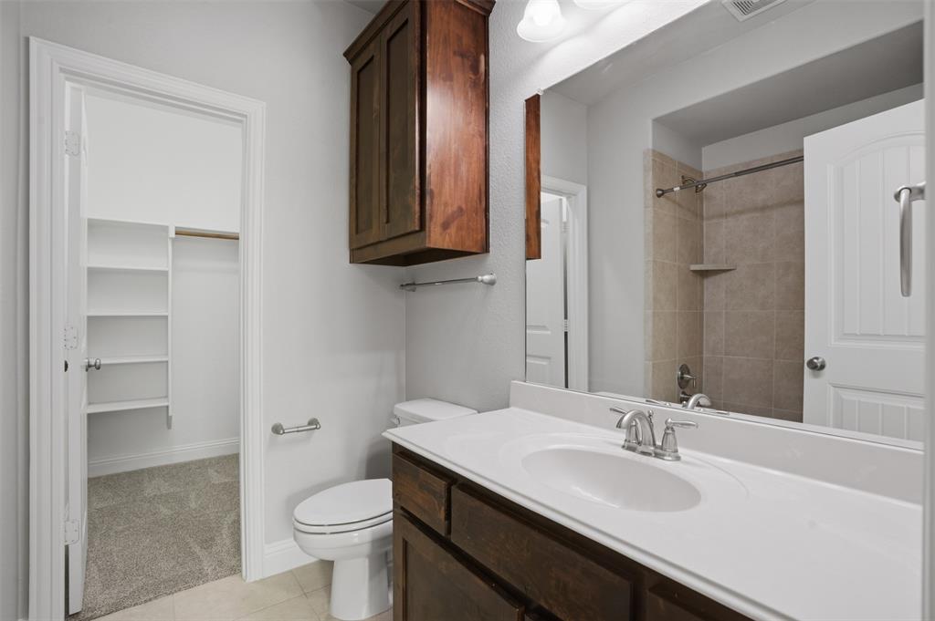 2217 Riviera Drive Little Elm, TX 75068 - Photo 20 of 36 Bathroom featuring a single vanity with a white countertop, dark wood-finish cabinetry, and a mirrored wall
