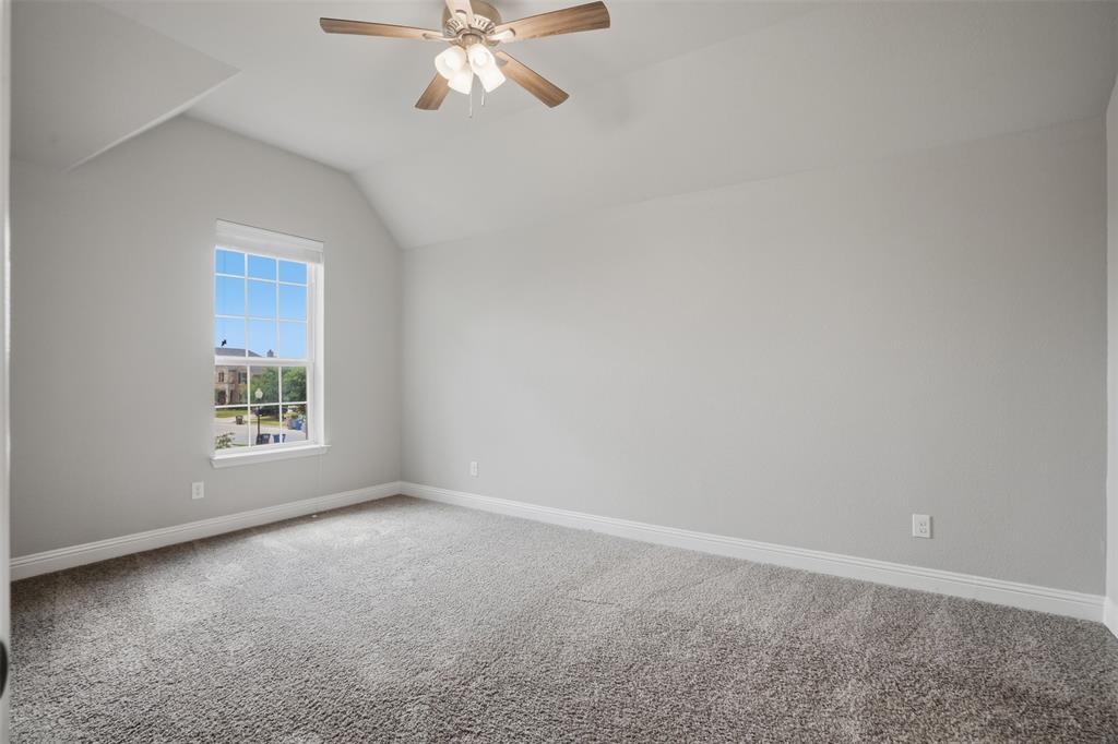2217 Riviera Drive Little Elm, TX 75068 - Photo 25 of 36 Spacious room featuring vaulted ceilings, light gray wall tones, plush carpet flooring, a large window with white framing, and a ceiling fan with integrated lighting